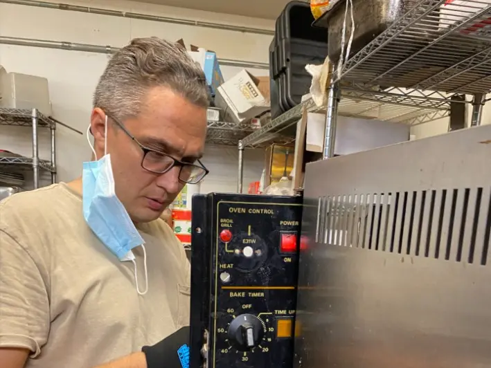 Roman working on commercial kitchen equipment at a customer’s location.